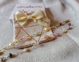 Delicate golden and silver beaded bracelets with a decorative bow and charms.