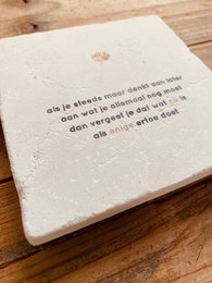 A unique, natural stone painting or coaster featuring inspirational Dutch text. The product is available in several variants with different text designs.