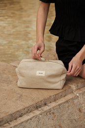  Beige toiletry bag with zipper closure and leather trim.