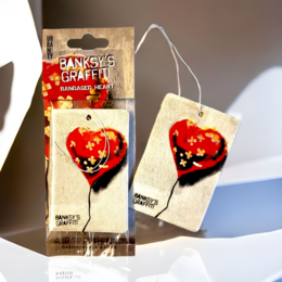Banksy Car Air Freshener - "Bandaged Heart" is a scented sachet featuring a heart-shaped design with a bandage motif, likely inspired by the iconic Banksy artwork. The product is packaged in a simple, minimalist style.