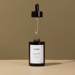 Organic and cold-pressed argan oil in a black bottle with a dropper. The product is suitable for body lotions.