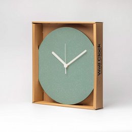 A round, minimalist wall clock with a green face and white hands, housed in a wooden frame.