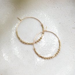 Gold-tone hoop earrings with the word "achtsam" engraved on them. The hoops have a simple, minimalist design and are suitable for everyday wear.
