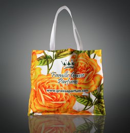  A large, reusable shopping bag featuring a vibrant orange rose design against a yellow floral background. The bag has a sturdy white handle and appears to be made of a durable, water-resistant material.