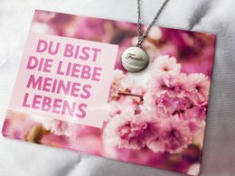 A pink gift card with the text "Du bist die liebe meines lebens" (You are the love of my life) against a background of pink blossoms.