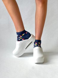 White sneakers with navy blue accents. Lace-up closure. Rounded toe shape. Comfortable and stylish women's athletic footwear.