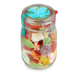 Colorful assortment of mixed candies in a glass jar with a decorative lid.