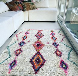 Colorful, patterned area rug with diamond and geometric shapes in vibrant hues of red, orange, blue, and white.