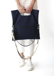 A navy blue tote bag with silver hardware and a minimalist design. The bag has a structured shape and a roomy interior, making it suitable for everyday use or as a work bag.