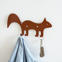 A brown squirrel-shaped wall hook for hanging children's clothing and accessories. Made of durable material, it features a simple, whimsical design that adds a touch of nature to any kid's room.