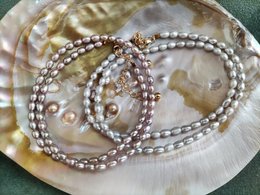Elegant pearl necklace with a delicate pendant, available in grey, purple, and white colors.