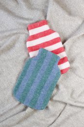 A striped hot water bottle cover in shades of blue and green.