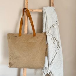 Vintage-style beige canvas tote bag with a simple design and minimal branding. Suitable for everyday use as a shoulder bag or shopping bag.