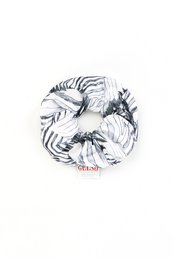 A white and black zebra print silk scrunchie with a red "GELSO" tag attached.