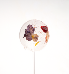  Sugar-free lollipop with freeze-dried wild strawberries and pantsy blooms. Round, colorful lollipop with visible freeze-dried fruit pieces and floral accents.