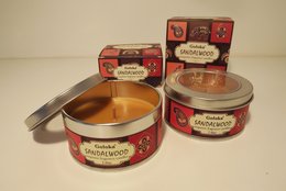 Scented candle in a round glass container, with a red and white label featuring the brand name "Goloka" and the scent "Sandalwood". The candle appears to be made of a solid wax material.