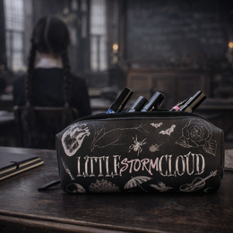 A black and white pencil case with a whimsical, mystical design featuring crescent moons, stars, and other celestial elements. The text "Wednesday - Mäppchen Storm Cloud" is prominently displayed.