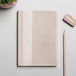 A neutral-colored notebook with an embossed textured cover design, featuring a minimalist and modern aesthetic.