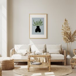  Framed art print featuring a black vase with green foliage. Neutral-toned living room decor with wooden furniture and accents.
