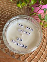  A round, tall candle with a rose quartz gemstone. The candle is scented with essential oils and has a hidden message that reads "I am light and love".