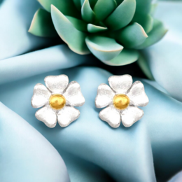 Delicate sterling silver stud earrings featuring small white daisy-like flowers. Suitable for everyday wear.