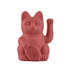  A red ceramic figurine of a lucky cat, also known as a Maneki-neko, sitting among red and black berries.