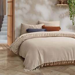 Cozy, oversized beige bedspread with tasseled trim and rustic, boho-inspired design. Ideal for creating a relaxed, natural ambiance in the bedroom.