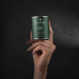 Cashew - Rosemary Garlic - Mini 55g. Covered nuts with rosemary and garlic flavors, in a green package with leaves and nuts.