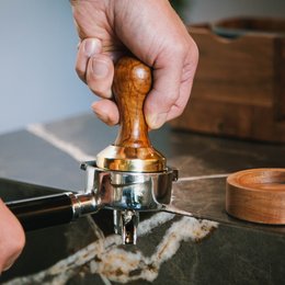 Wooden espresso tamper with holder, made of durable materials for consistent coffee tamping.