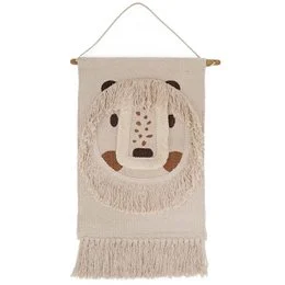 The image shows a decorative wall hanging featuring a whimsical, smiling face design. The wall hanging appears to be made of a textured, woven material and is hung on a wooden wall. The overall style and design suggest this is a children's room decor item.