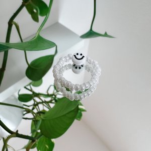 Pearl ring made of white glass beads with a smiley face in white