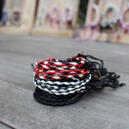  Handmade leather bracelets in various color combinations including red/white/black, red/white/blue, orange, red/black/yellow/green, cream, black, black and white, and orange/yellow/green/pink. The bracelets feature a woven design and are made in Bali.