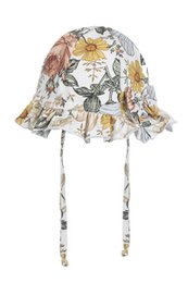 A white summer hat for girls featuring a floral print design with yellow flowers. The hat has a ruffled brim and adjustable chin strap for a comfortable fit.