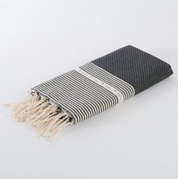 A black and white striped hammam towel or fouta with a waffle texture, measuring 100x200cm.