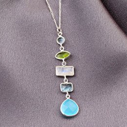 This sterling silver necklace features a pendant with a mix of gemstones, including a green gemstone, a white gemstone, and a blue teardrop-shaped gemstone. The pendant hangs from a delicate silver chain.