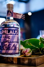 Dry gin with 43% alcohol content, featuring a glass bottle with a label displaying the brand name "Applause" and various decorative elements.