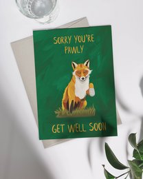 A greeting card featuring a cute fox illustration with the text "Sorry you're poorly, get well soon" on a green background.