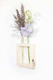 Decorative vase with dried flowers and greenery. Wooden frame with minimal design.