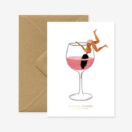 A birthday card featuring a whimsical illustration of a person diving into a glass of pink cocktail.