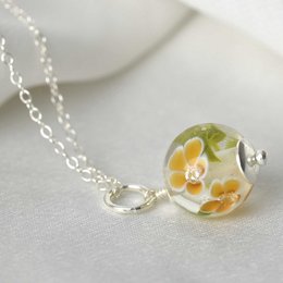 Essential necklace with amber glass flowers. Delicate glass pendant with real dried flowers and amber-colored glass. Elegant and nature-inspired design.