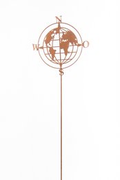 A copper-colored garden sculpture in the shape of a globe with compass directions, mounted on a metal stake.