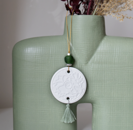 Elegant green ceramic diffuser with dried floral arrangement, featuring a round white ceramic pendant with a tassel accent.
