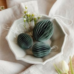 Paper Easter eggs in soft pink color, arranged on a white plate with spring flowers.