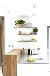 White wall-mounted shelves with wooden accents, displaying various household items and decor.