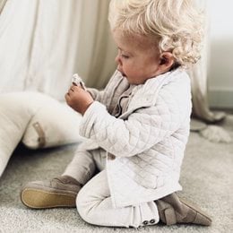 Taupe suede baby boots with velcro closure and soft soles, suitable for infants and toddlers.