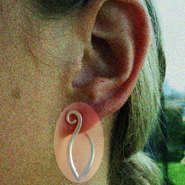 Elegant silver-toned statement earrings with a unique spiral design. The earrings feature a modern, abstract shape that adds a touch of sophistication to any outfit.