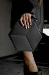 A black hexagonal handbag with a minimalist, geometric design. The handbag has a sleek, modern appearance and appears to be made of a durable, high-quality material.
