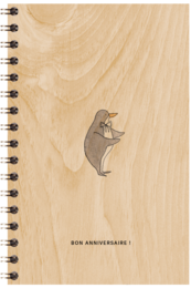 A wooden poster with a small bear graphic and the text "BON ANNIVERSAIRE!" (Happy Birthday in French). The poster has a spiral binding and a light wood grain background.