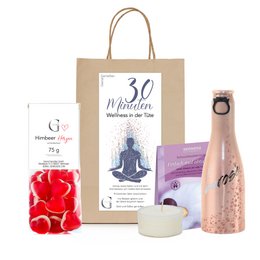 "Gift bag containing a variety of wellness products, including a 30-minute wellness gift set, chocolate, and rose petals. Ideal for relaxation and self-care."