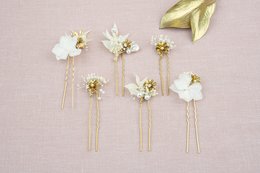 Elegant white floral hair clips with gold accents, perfect for formal occasions or weddings.